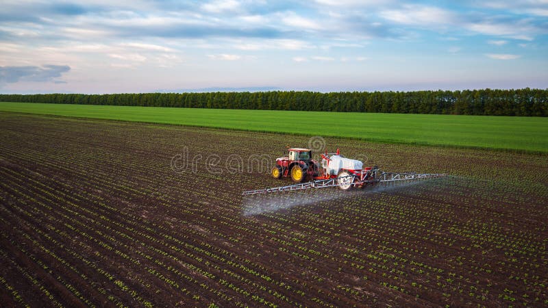 Farming tractor spraying on field at spring stock photo