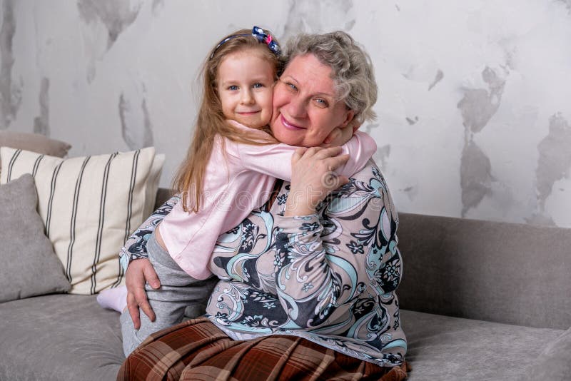 Farmodern och hennes lilla sondotter h?ller ?gonen p? filmer tillsammans och spelar p? apparaten, medan sitta p? soffan royaltyfri fotografi Farmodern och hennes lilla sondotter h?ller ?gonen p? filmer tillsammans och spelar p? apparaten, medan sitta p? soffan royaltyfri fotografi
