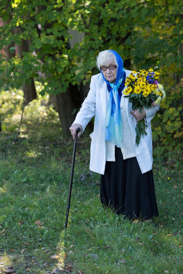 Farmor med en rotting och blommor på bakgrunden av träd