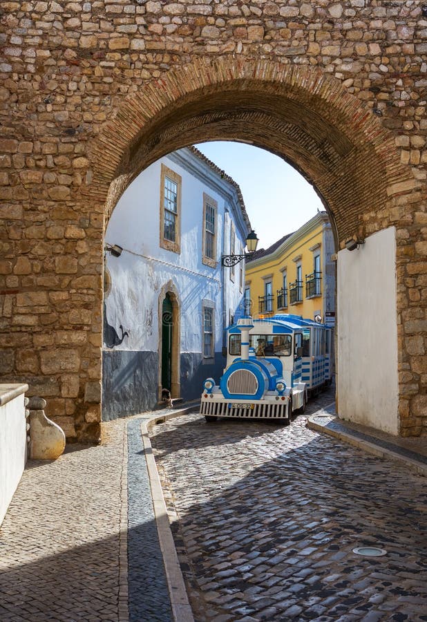 Faro, Algarve, Portogallo 29 aprile 2018: Tram turistico che passa tramite la via d'avvolgimento stretta del centro storico di Fa fotografie stock libere da diritti