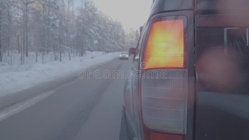 Faro posteriore SUV sulla strada di inverno, luce rossa Chiuda su di grande automobile nera dalla retrovisione su una strada dell