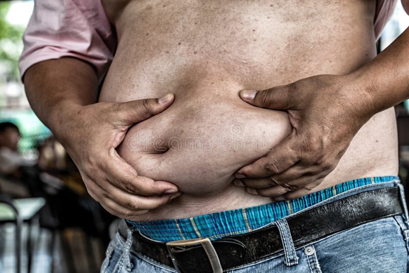 Farorna av bukfett , Pressar den sjukligt feta mannen i jeans buken arkivfoto Farorna av bukfett , Pressar den sjukligt feta mannen i jeans buken arkivfoto