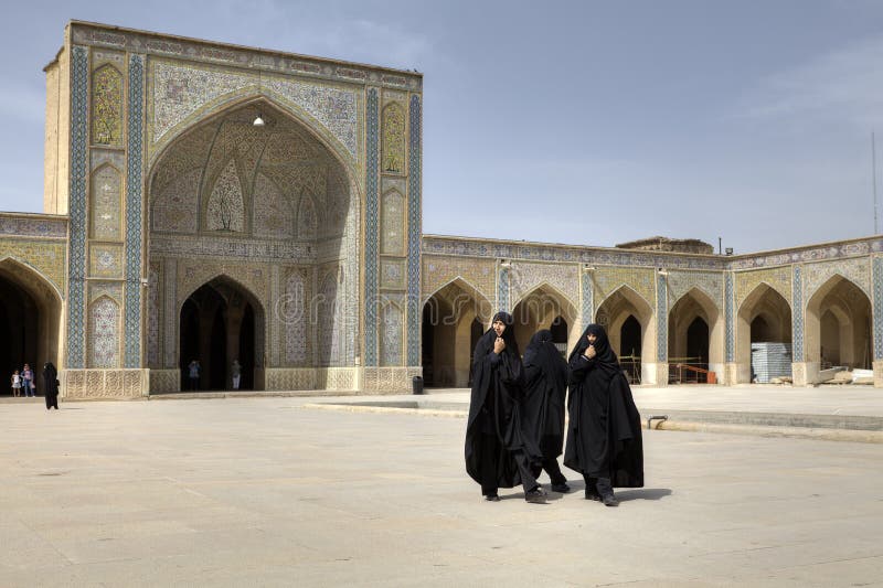 Iranian women wearing black islamic dresses in inner courtyard M