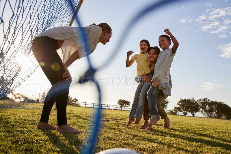Farsan lyfter hans son och dotter under en familjfotbolllek royaltyfri fotografi Farsan lyfter hans son och dotter under en familjfotbolllek royaltyfri fotografi