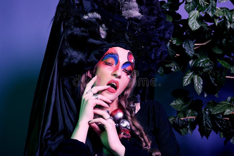Fashion, beauty, people and halloween concept: Young woman with a bright creative make-up and a big black headdress. stock photos Fashion, beauty, people and halloween concept: Young woman with a bright creative make-up and a big black headdress. stock photos