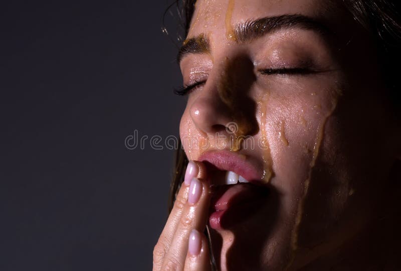 Fashion and beauty. Sensual young woman face with honey drop close up. Sexy model with honey drip on face.