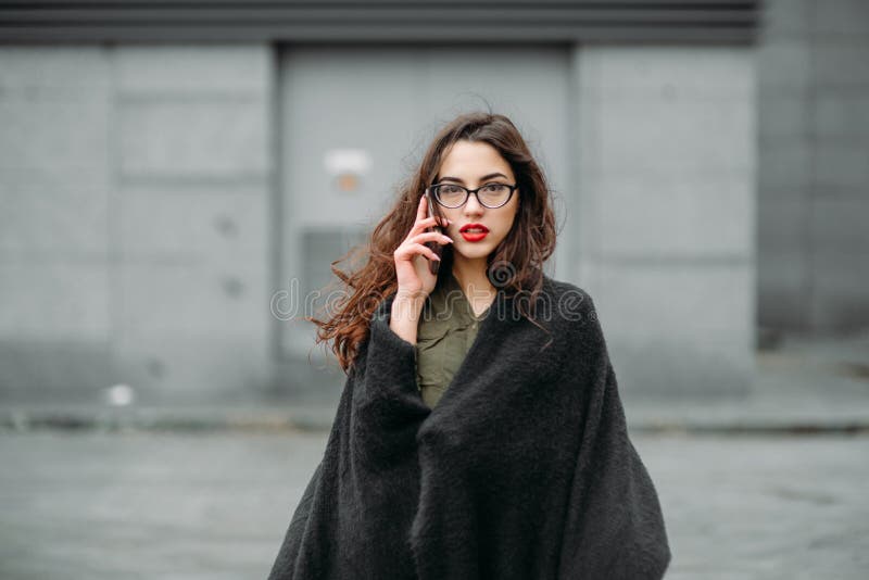 Fashion consept: beatiful young girl with long hair, glasses, red lips standing near modern wall wearing in green suit and grey je stock image Fashion consept: beatiful young girl with long hair, glasses, red lips standing near modern wall wearing in green suit and grey je stock image