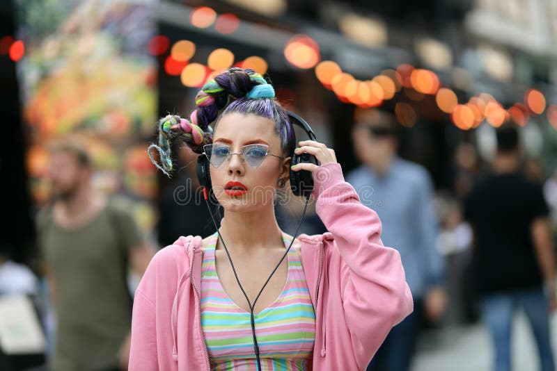 Fashion cool funky girl in headphones listening to music wearing colourful pink sweater and fancy sunglasses royalty free stock photo Fashion cool funky girl in headphones listening to music wearing colourful pink sweater and fancy sunglasses royalty free stock photo
