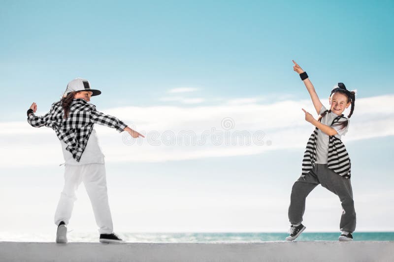 Fashion kids pointing on copy space over sky background.