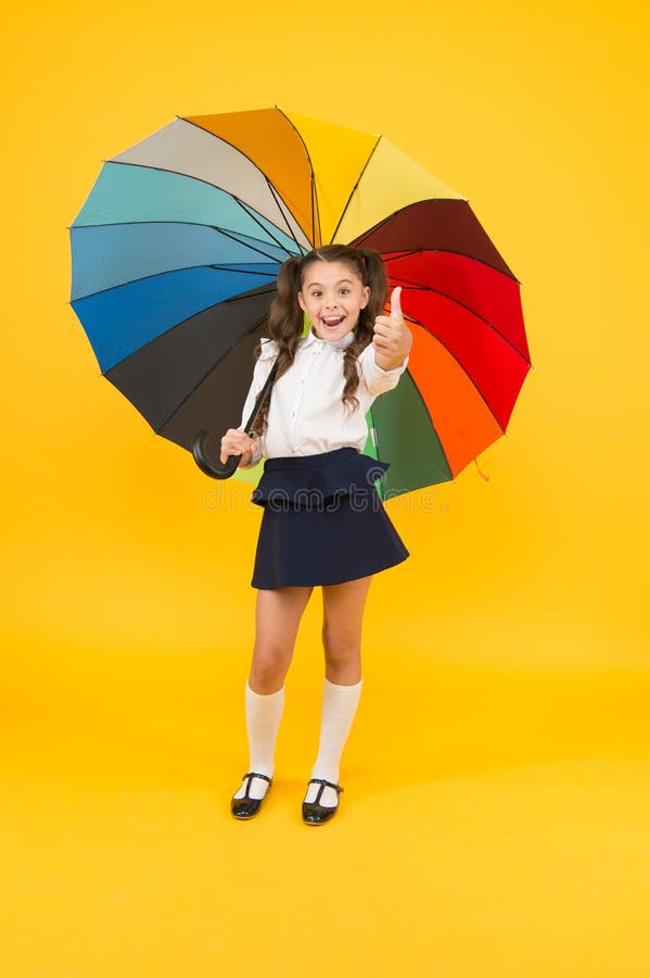 Fashion knowledge. Happy schoolchild with fashion look giving thumbs up on yellow background. Little child holding.