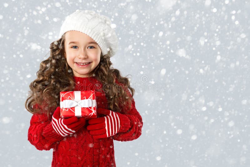 Fashion little girl with Christmas gift, on snow background