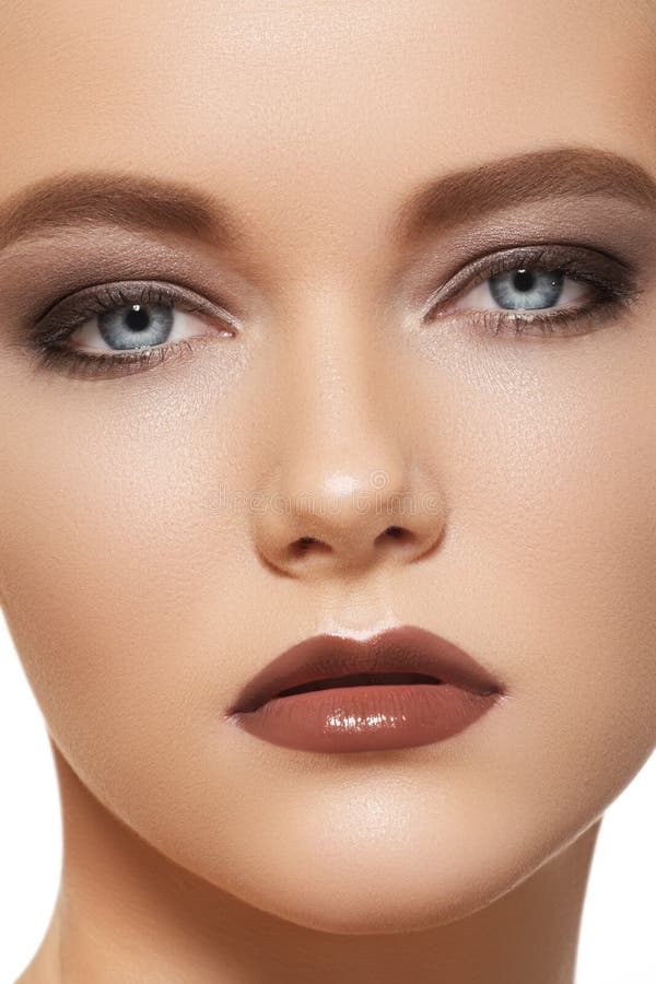 Close-up portrait of beautiful young woman model with fashion evening make-up, clean skin and brown gloss on lips. Close-up portrait of beautiful young woman model with fashion evening make-up, clean skin and brown gloss on lips