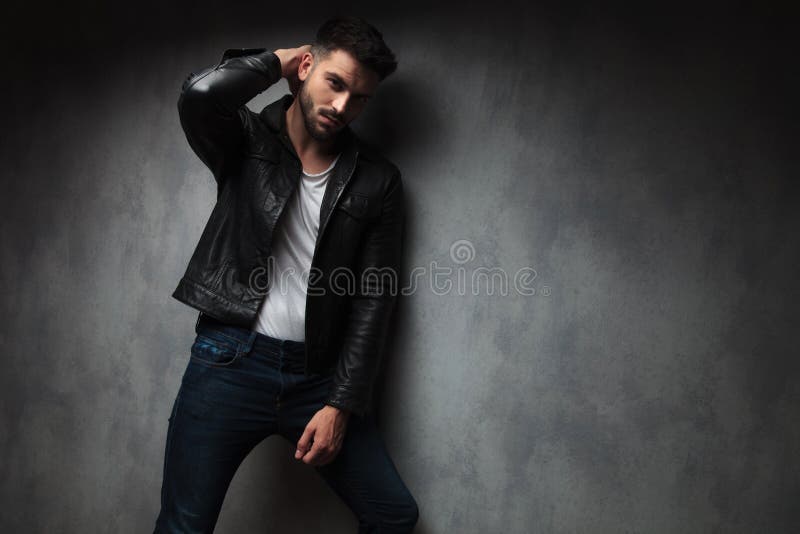 Fashion man in leather jacket posing with hand behind head