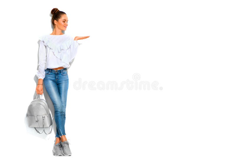 Fashion model brunette girl full length portrait in blue jeans and white shirt , backpack, in sneakers modern shoes