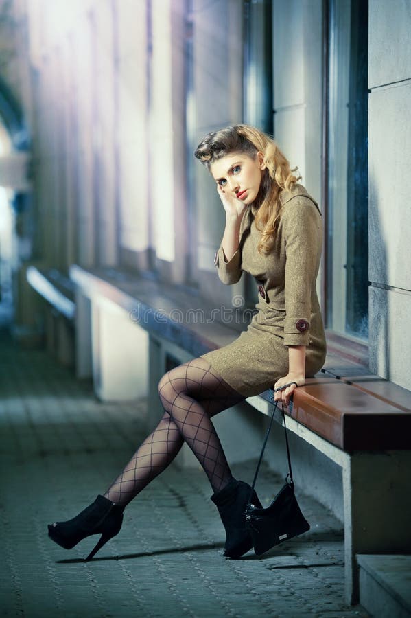 Long Legs Fashion Blonde Girl Sitting on Bench. Street Fashion. Stock Photo