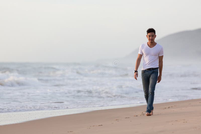 Fashion model man walking on the sand beach stock images