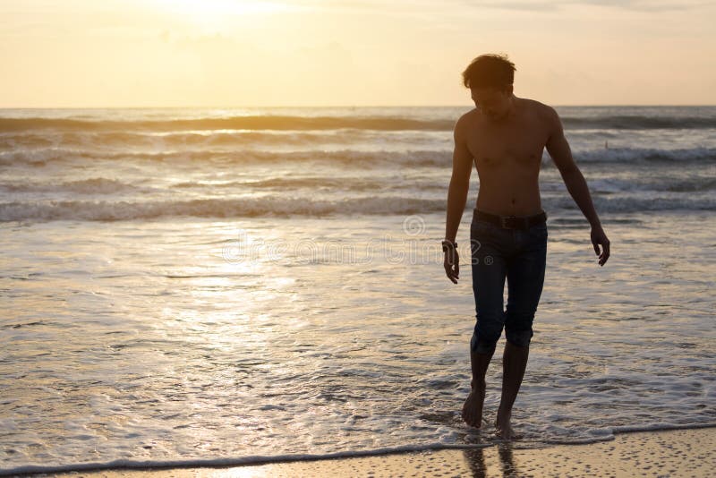 Fashion model man walking on the sand beach royalty free stock photo