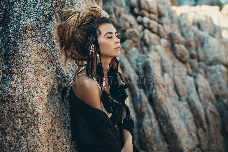 Fashion model portrait outdoors. boho style young woman with headdress made of feathers