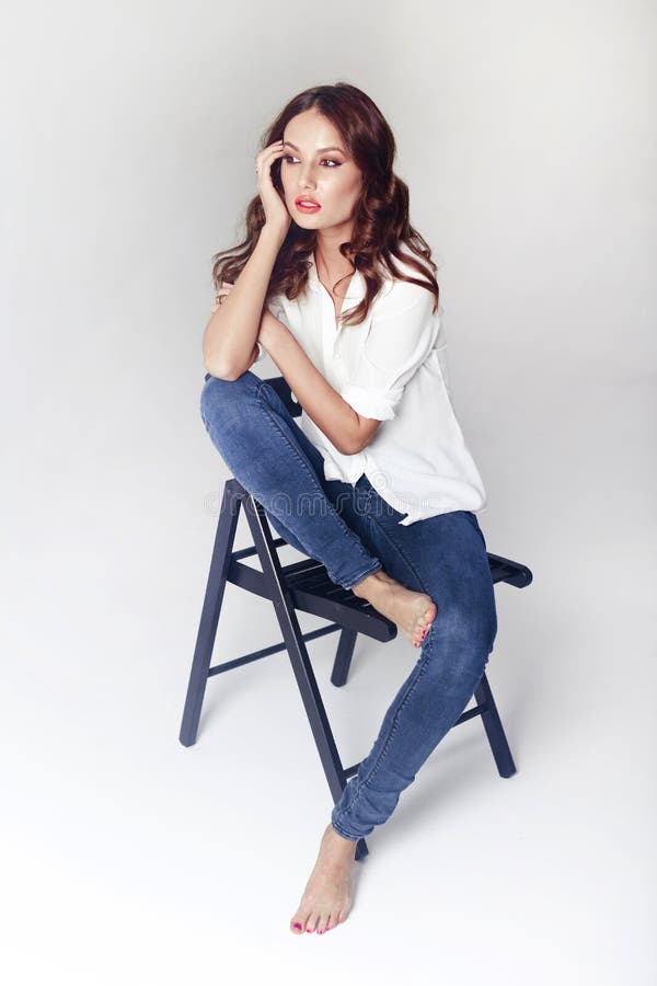 Fashion Model Sitting on a Chair in a Blouse and Jeans Barefoot Stock ...