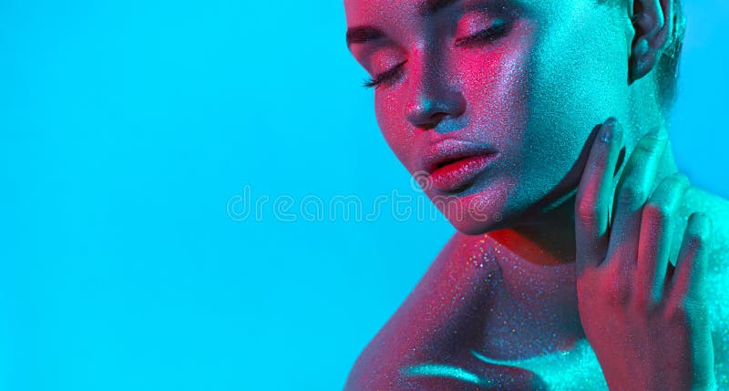 Fashion model woman in colorful bright sparkles and neon lights posing in studio