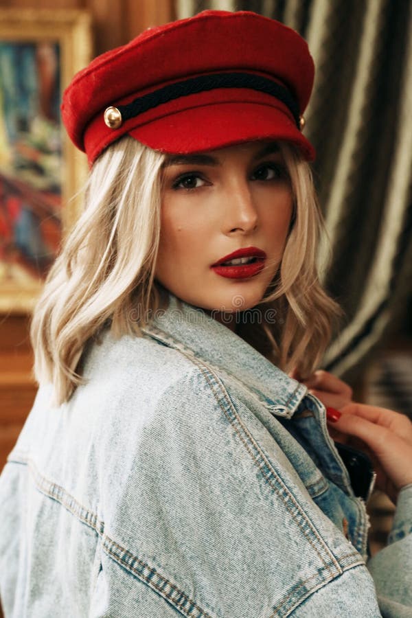 Beautiful woman with blond hair in casual clothes and red hat sitting in cafe