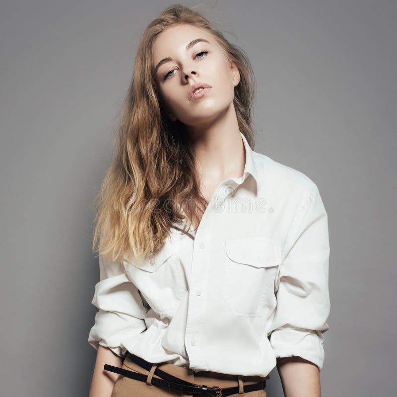 Fashion portrait of a beautiful young blonde woman in a white shirt in the studio on a gray background stock images Fashion portrait of a beautiful young blonde woman in a white shirt in the studio on a gray background stock images