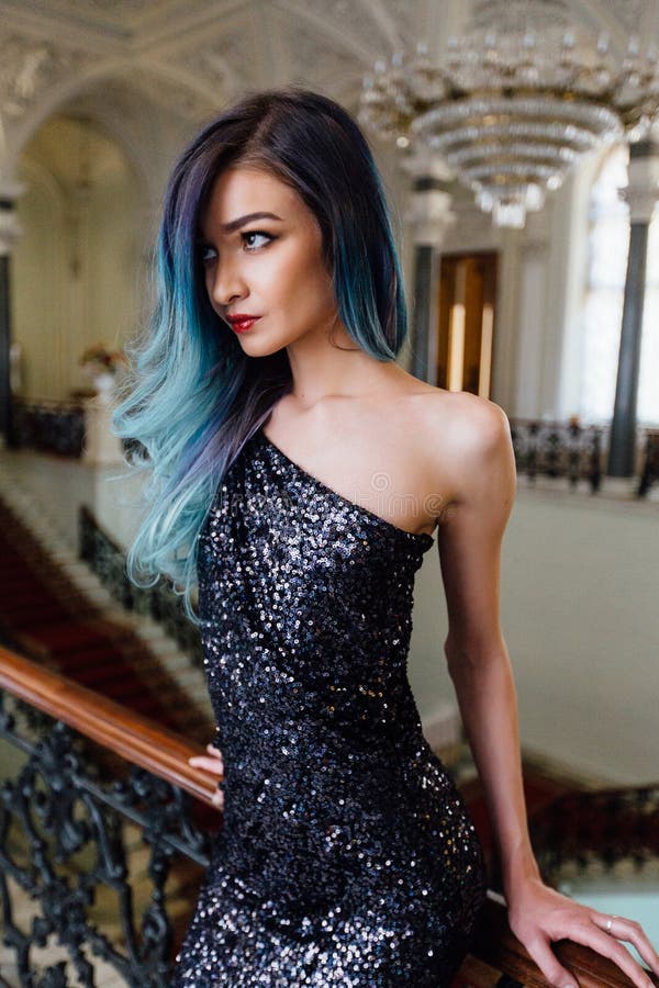 Fashion portrait of gorgeous girl with blue dyed hair long. The beautiful evening cocktail dress.