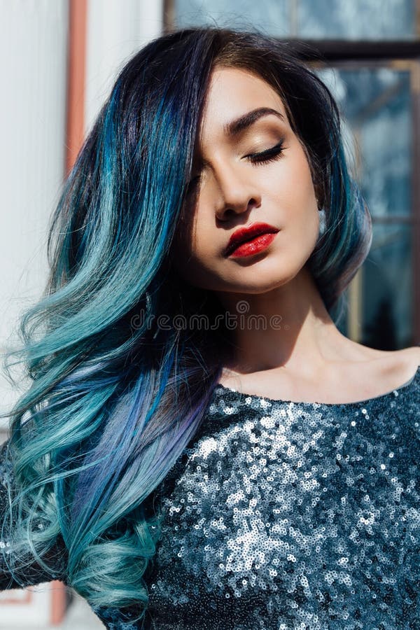 Fashion portrait of gorgeous girl with blue dyed hair long. The beautiful evening cocktail dress.