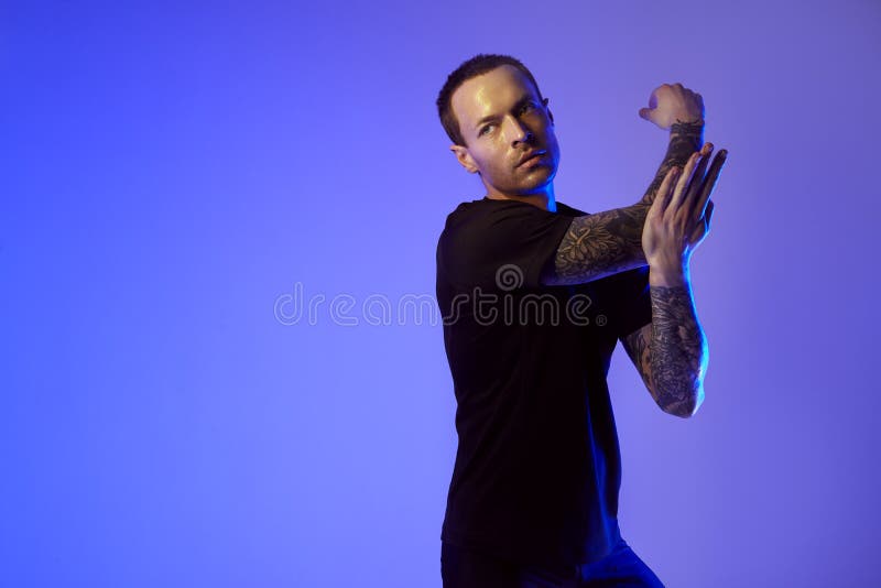 Fashion portrait of sport fit attractive man making arm stretch. Masculine naked torso, tattooed hands, hipster look. Color flash stock images Fashion portrait of sport fit attractive man making arm stretch. Masculine naked torso, tattooed hands, hipster look. Color flash stock images