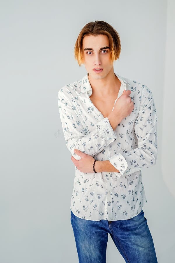 Fashion portrait of young man in white shirt poses over grey wall stock photo Fashion portrait of young man in white shirt poses over grey wall stock photo