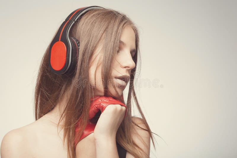 Fashion pretty girl listening music with headphones, wearing red gloves, take pleasure with song. Lifestyle woman concept