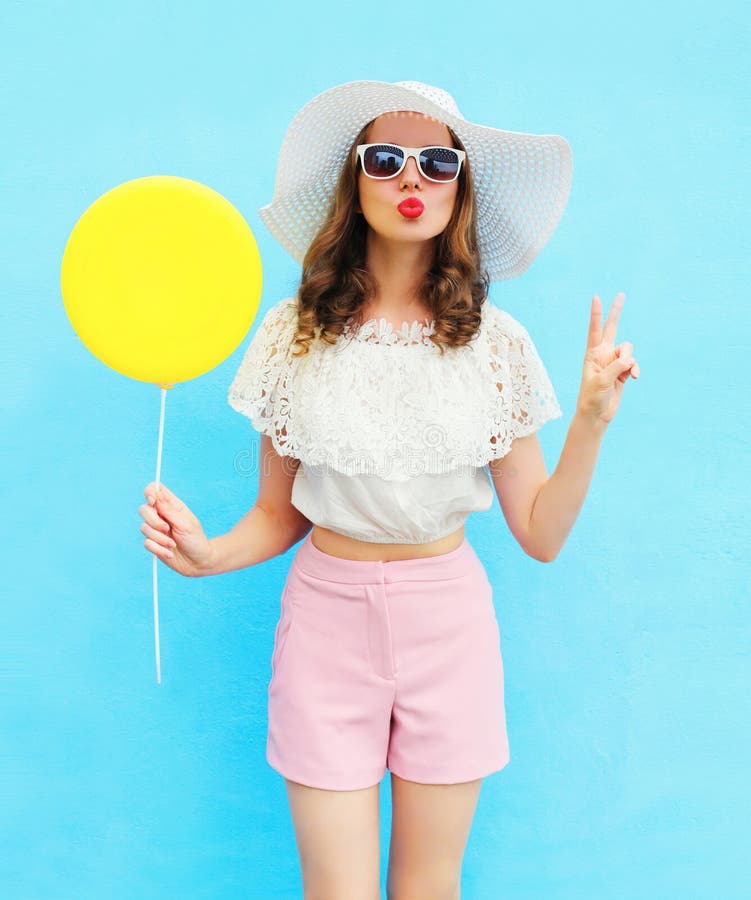 Fashion pretty woman in straw hat with air balloon over blue