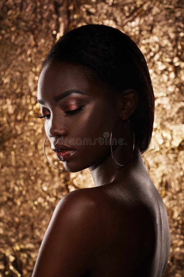 Fashion studio portrait of an extraordinary beautiful african american model with closed eyes over golden background