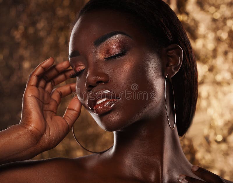 Fashion studio portrait of an extraordinary beautiful african american model with closed eyes over golden background