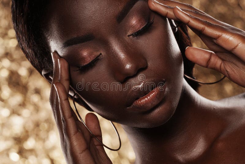 Fashion studio portrait of an extraordinary beautiful african american model with closed eyes  over golden background