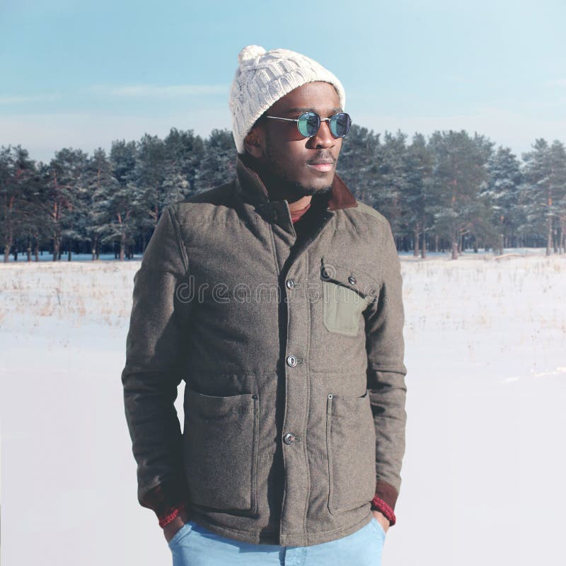 Fashion stylish young african man wearing a sunglasses and jacket with knitted hat in winter