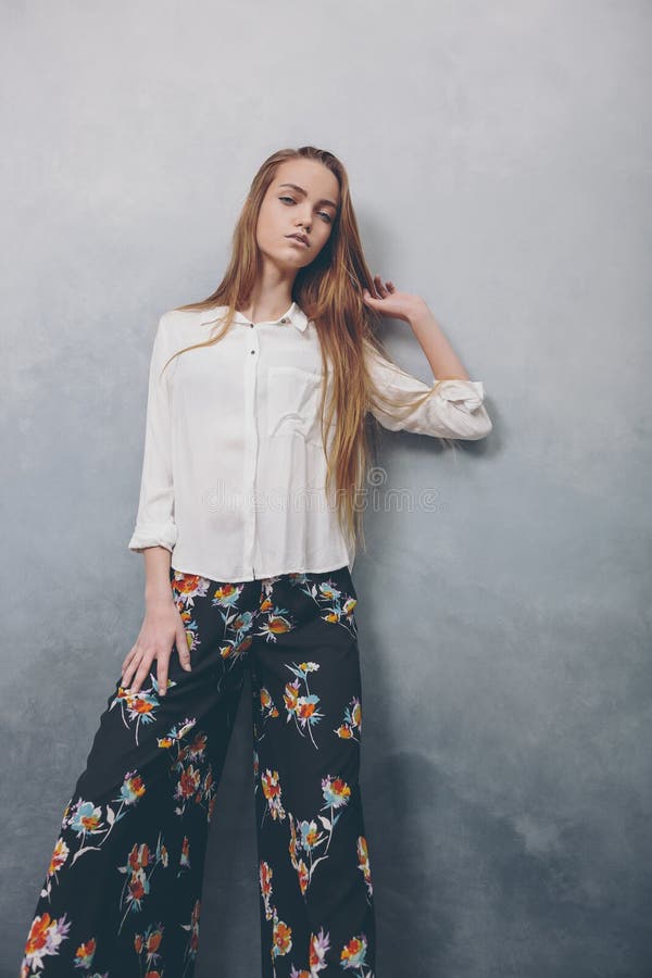 Fashion teenager girl standing against blue textured grunge wall background.