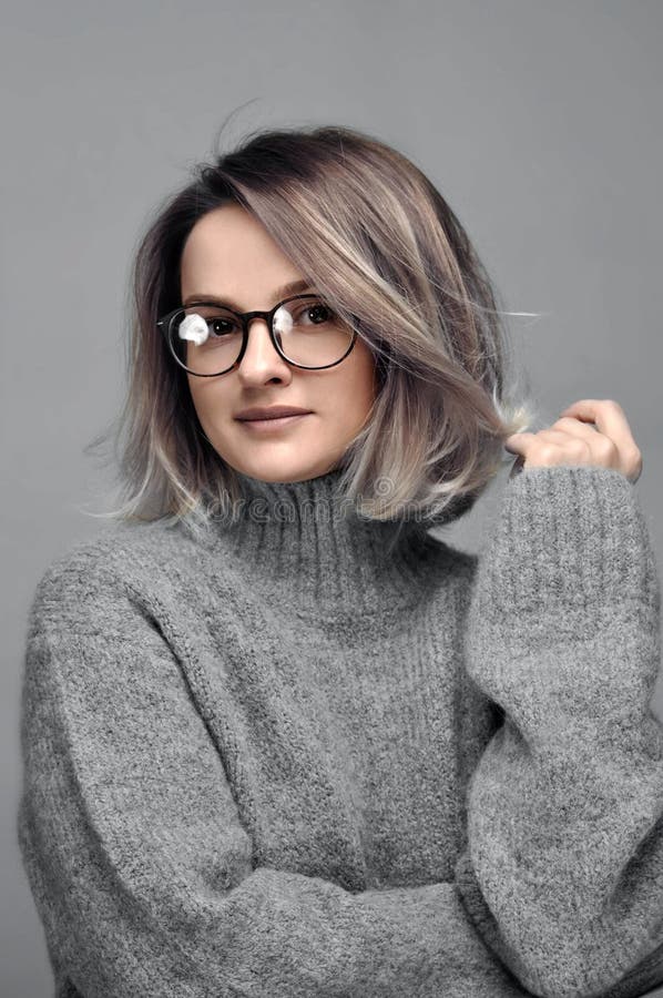 Fashion woman in eyeglasses wearing stylish grey sweater royalty free stock photography Fashion woman in eyeglasses wearing stylish grey sweater royalty free stock photography