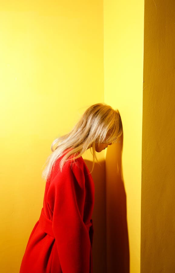 Fashion young girl blogger dressed in stylish red coat poses on the background of yellow walls in the show room royalty free stock photos Fashion young girl blogger dressed in stylish red coat poses on the background of yellow walls in the show room royalty free stock photos
