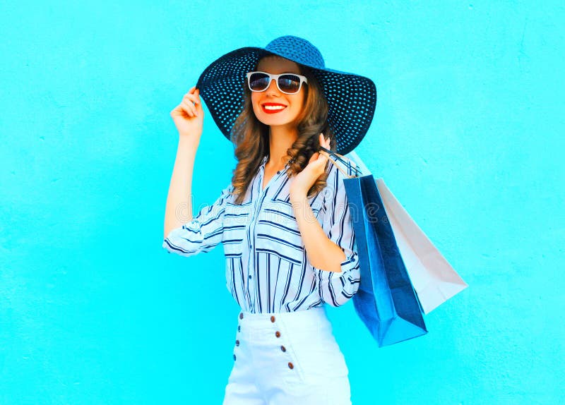 Fashion young smiling woman wearing a shopping bags, straw hat