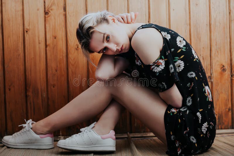 Fashionable woman blonde in dress with flowers sits on the floor. Fashionable woman blonde in dress with flowers sits on the floor