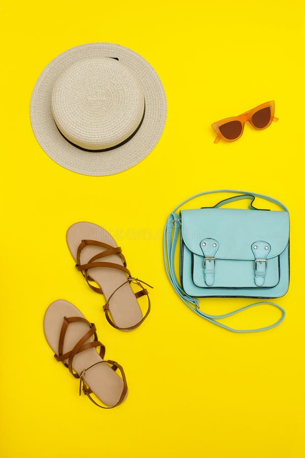 Fashionable concept. Women`s beach hat, handbag, brown shoes. Yellow background. Flat lay