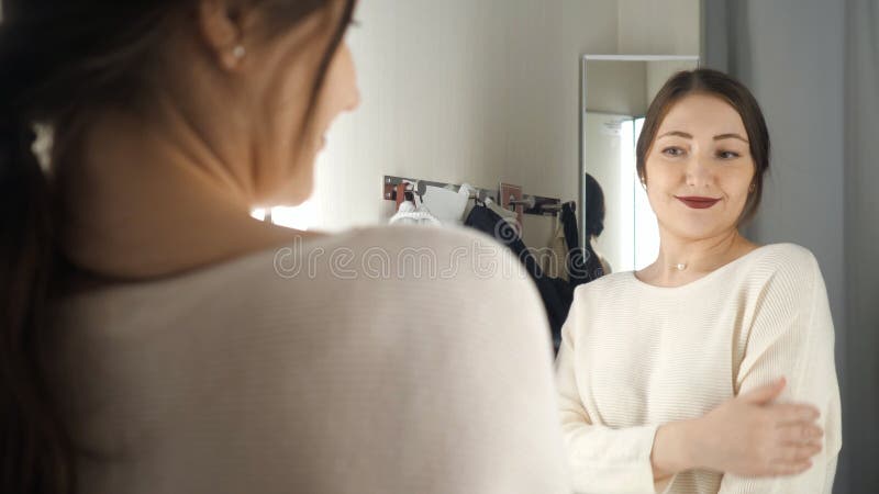 Fashionable girl looking in the mirror in fitting room