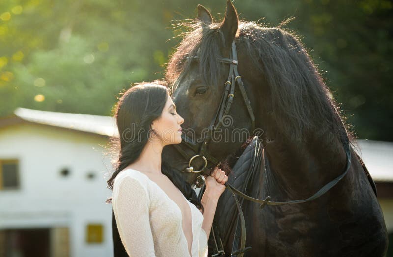 Fashionable lady with white bridal dress near brown horse. Beautiful young woman in a long dress posing with a friendly horse royalty free stock images Fashionable lady with white bridal dress near brown horse. Beautiful young woman in a long dress posing with a friendly horse royalty free stock images