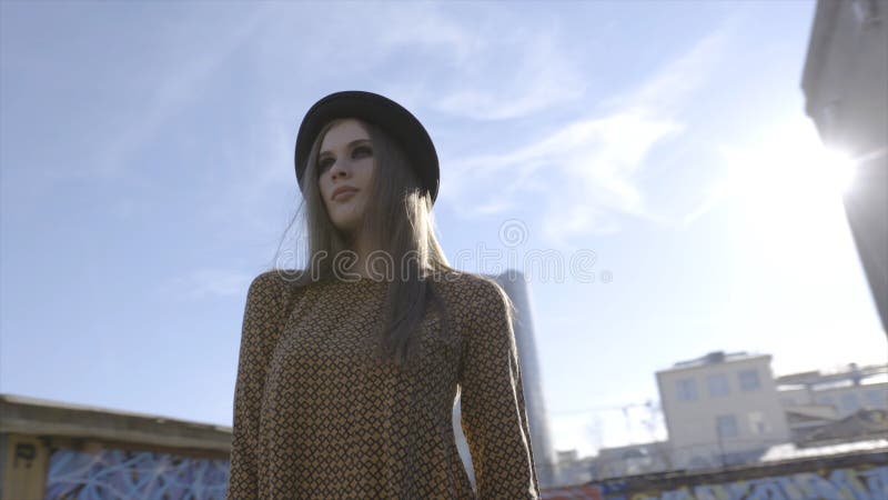 Fashionable young woman model in hat posing on camera. Action. Outdoor portrait of young beautiful fashionable woman stock photo Fashionable young woman model in hat posing on camera. Action. Outdoor portrait of young beautiful fashionable woman stock photo