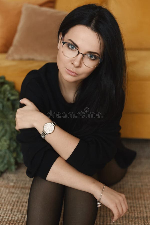 A fashionable young woman with perfect dark hair and perfect makeup in an elegant black dress. Beautiful brunette model