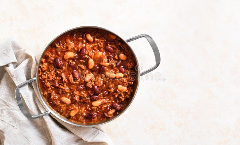 Fasola kowbojska w kuchni. Fasola kowbojska z mielonym pieprzem jalapeno i bekonem w patelni do gotowania na jasnym tle. płaski widok górny