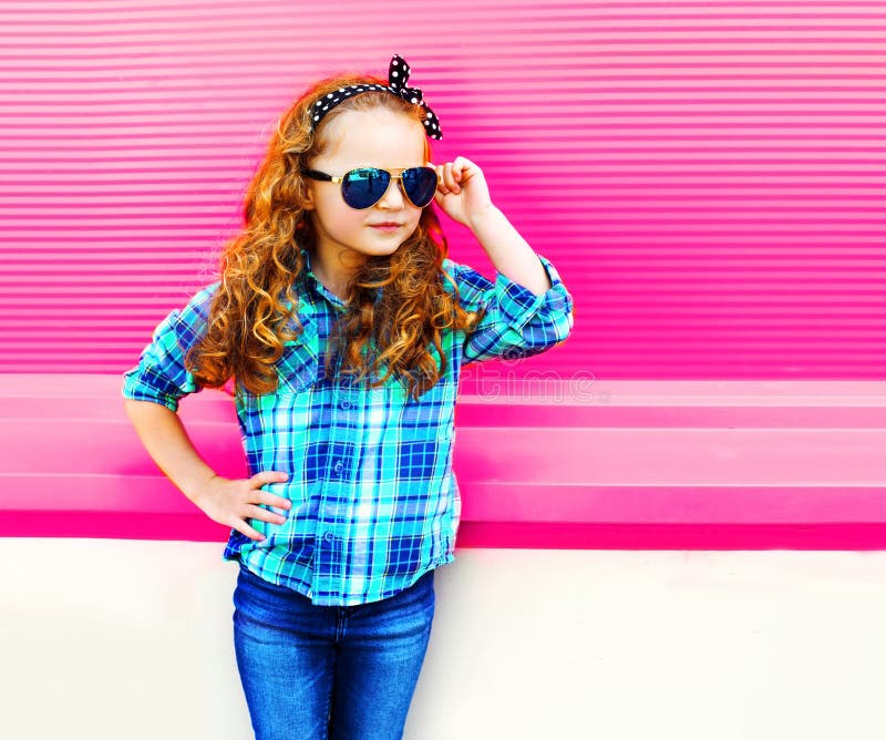 Fasonuje portret małej dziewczynki dziecka w w kratkę koszula, okulary przeciwsłoneczni pozuje na kolorowych menchiach zdjęcia stock Fasonuje portret małej dziewczynki dziecka w w kratkę koszula, okulary przeciwsłoneczni pozuje na kolorowych menchiach zdjęcia stock