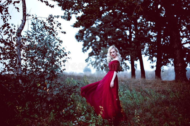 Fasonuje wspaniałej młodej blondynki kobiety w pięknej czerwieni sukni w baśniowej lasowej magicznej atmosferze Retuszujący tonow obrazy royalty free Fasonuje wspaniałej młodej blondynki kobiety w pięknej czerwieni sukni w baśniowej lasowej magicznej atmosferze Retuszujący tonow obrazy royalty free
