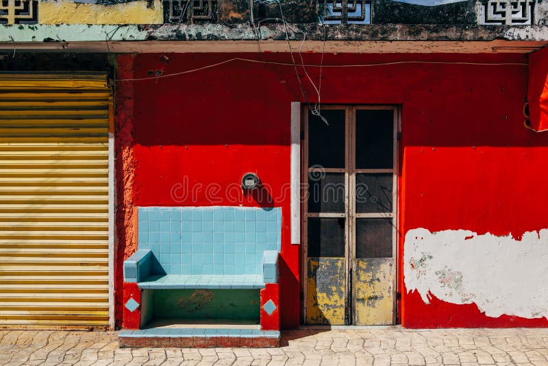 Fassade eines mexikanischen Hauses auf der Insel von Cozumel Rote schäbige Wand und blaue Bank stockbild Fassade eines mexikanischen Hauses auf der Insel von Cozumel Rote schäbige Wand und blaue Bank stockbild